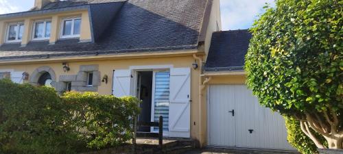 a house with white garage doors and a roof at Ile du Ponant in Ploemeur