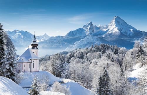 una iglesia en la nieve con montañas en el fondo en KitzMoments by Belle Stay en Reith bei Kitzbühel