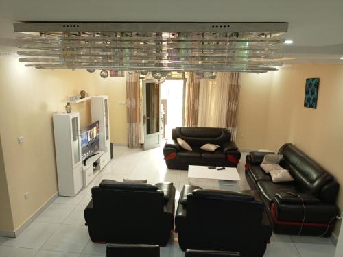 a living room with black leather furniture and a television at Kigali Peace villa in Kigali