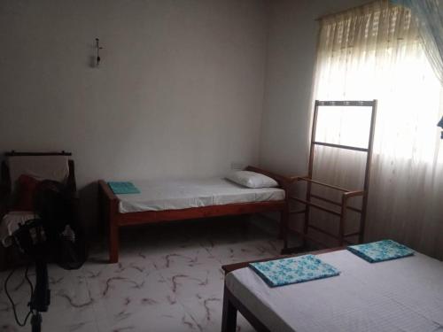 Cette petite chambre comprend 2 lits et une fenêtre. dans l'établissement Kandyan Guest house, à Kandy
