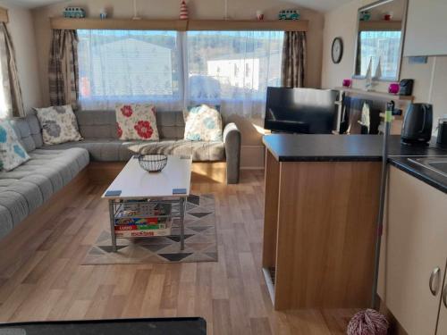 una cucina e un soggiorno con divano e tavolo di hollies retreat a Lossiemouth