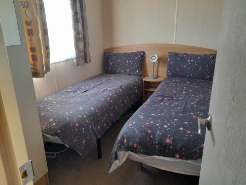 een slaapkamer met 2 bedden en een lamp op een tafel bij hollies retreat in Lossiemouth