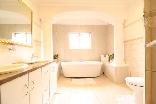een witte badkamer met een bad en een wastafel bij Smartz Luxury Home in Centurion