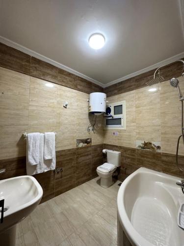 a bathroom with a tub and a toilet and a sink at Crowne Pyramids view inn in Cairo