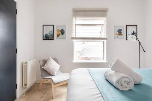 een slaapkamer met een bed, een stoel en een raam bij Top Floor, City Centre, Parking in Belfast