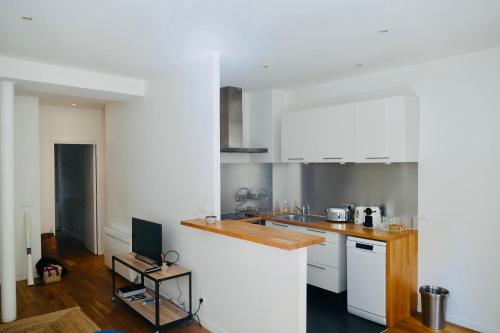 une cuisine avec des armoires blanches et un comptoir dans l'établissement Appartement Cosy Louvre Sentier, à Paris