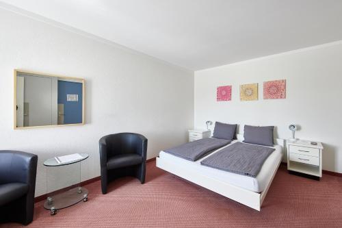 a bedroom with a bed and two chairs and a mirror at Hotel Rotes Haus in Brugg