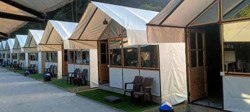 a row of white tents with chairs and windows at Kabila Camp in Kasol