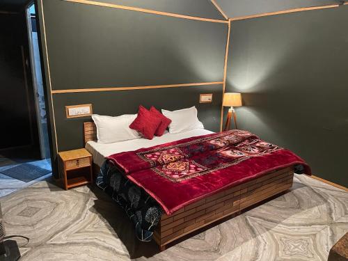 a bedroom with a bed with a red blanket on it at Kabila Camp in Kasol