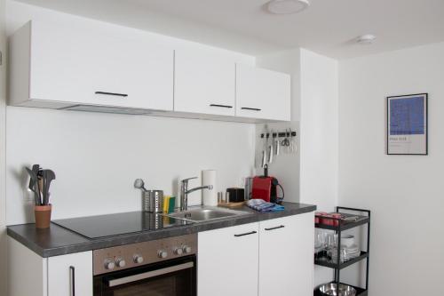 uma cozinha com armários brancos e um lavatório em City Apartments Dornbirn Gemütliches Apartment im Stadtzentrum Dornbirn, Kopenhagen 5 em Dornbirn