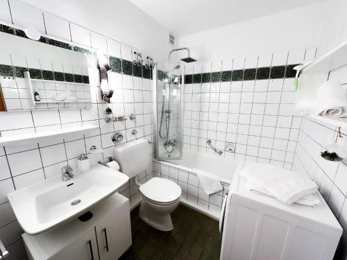 a white bathroom with a sink and a toilet and a tub at Gipfelsicht in Oberstaufen