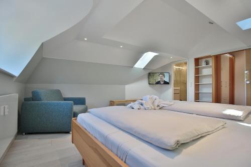- une chambre avec un grand lit et une chaise bleue dans l'établissement Haus Schäfer, à Timmendorfer Strand