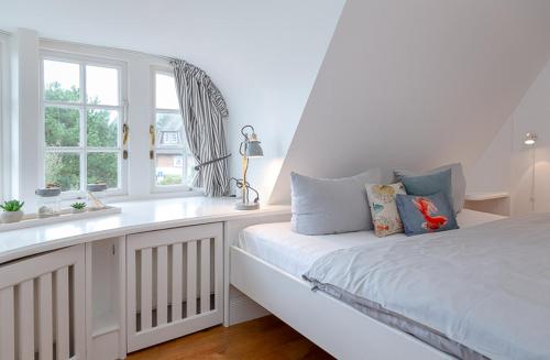 a white bedroom with a bed and a window at Watt Hüs Munkmarsch in Munkmarsch