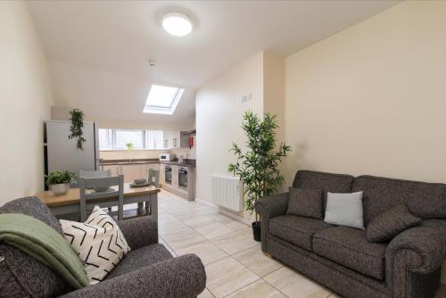 a living room with two couches and a kitchen at cheerful double en-suite with free wifi in Derby