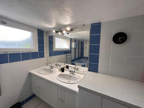 La salle de bains est pourvue de 2 lavabos et d'une horloge murale. dans l'établissement La Souste appartement avec jardin privatif, à La Fare-en-Champsaur