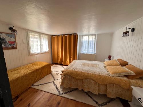 una camera con 2 letti e tende arancioni di La Souste appartement avec jardin privatif a La Fare-en-Champsaur