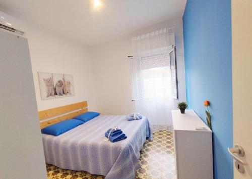 a bedroom with a bed with blue walls and a window at Casa Cristina Beach in Marina di Ragusa