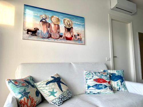 een schilderij aan de muur boven een witte bank met kussens bij Beach Front Apartment Sabbiadoro in Lignano Sabbiadoro