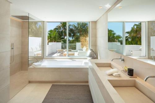 a bathroom with a tub and a large window at Stunning Duplex Apartment in Puente Romano Resort in Marbella