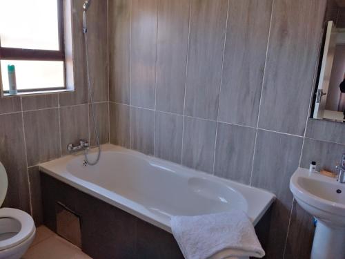 a bathroom with a tub and a toilet and a sink at Chobe Blue Guest Inn in Kasane