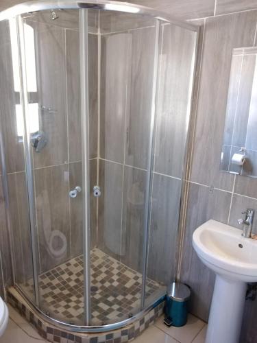 um chuveiro com uma porta de vidro ao lado de um lavatório em Chobe Blue Guest Inn em Kasane