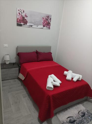 un letto rosso con due asciugamani bianchi sopra di LA casetta 2.0 a Termini Imerese