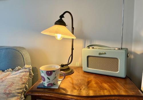 a table with a cup and a lamp and a microwave at Cobblers Lodge in Lyme Regis