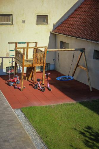 a chair and a swing and a tricycle on a patio at La Róna Rooms in Kiskőrös