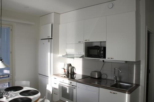 une cuisine blanche avec un évier et un micro-ondes dans l'établissement Apartment with Sauna in the heart of Rovaniemi, à Rovaniemi