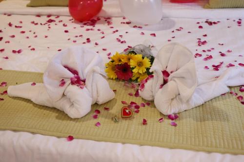 a pair of towels and flowers on a bed at SKD RESORT AND CLUB in Barvāla