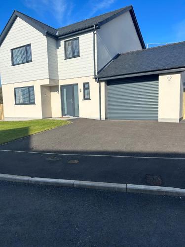 a white house with a garage on a street at Garreg Fawr Trearddur Bay - Ty Oren in Trearddur