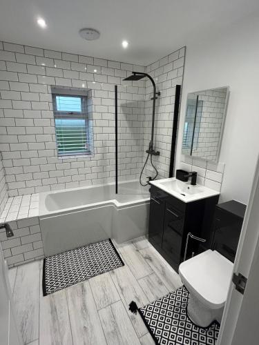 a bathroom with a tub and a toilet and a sink at Garreg Fawr Trearddur Bay - Ty Oren in Trearddur