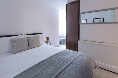 a bedroom with a white bed and a mirror at Modern, Luxurious 1BR Flat- Heart of Covent Garden in London