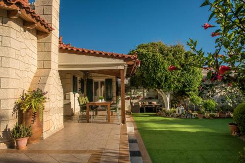 a house with a patio and a grass yard at SeaSide Gem Private Villa Olia with Heated Pool in Kato Gouves