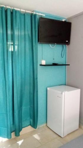 una camera con tenda blu e frigorifero di L'arbre à Pain a Tsingoni