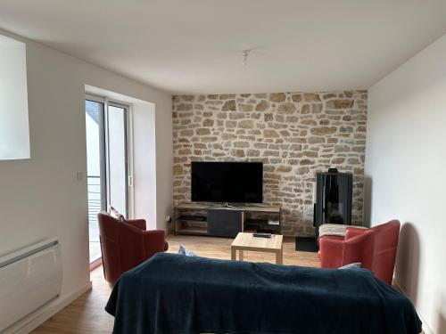 - un salon avec un mur en briques et une télévision dans l'établissement TI YANN, à Porspoder