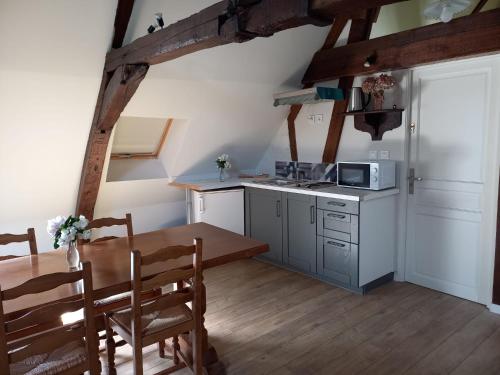 a small kitchen with a table and a microwave at Le gîte des Géants in Le Quesnoy