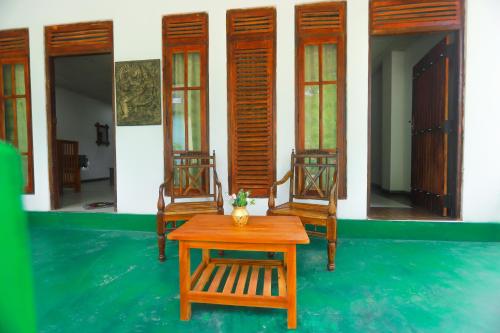 two chairs and a table in front of a house at Jm Resort in Dambulla