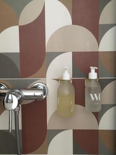 uma casa de banho com duas garrafas de sabão na parede em Le bois de mon coeur - studio cosy indépendant 