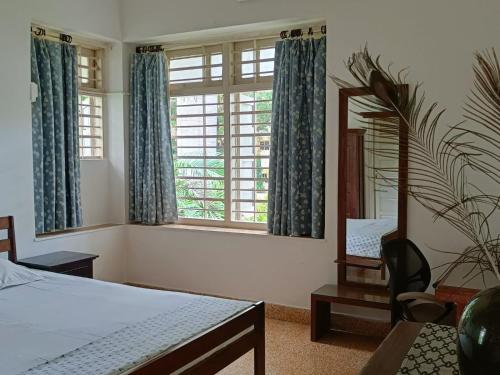 a bedroom with a bed and a mirror and a chair at Srinekatan Heritage Villa Homestay in Ahmedabad