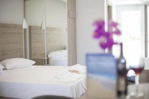 a bedroom with a white bed and a mirror at Aggelos Apartments & Deluxe Studios in Nydri