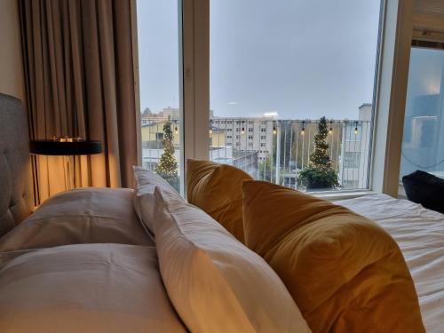 a bed with pillows in front of a large window at Premier Residences Helsinki in Helsinki