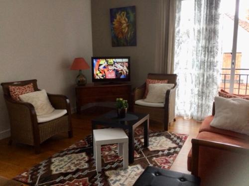 ein Wohnzimmer mit einem Sofa, Stühlen und einem TV in der Unterkunft Pierre de lune in Descartes