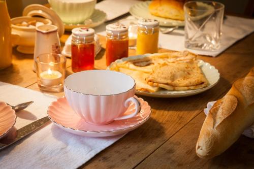 a wooden table with a cup and plates of food at Il Etait Une Fois Chez Moi La Chambre Augustin in Le Loroux-Bottereau