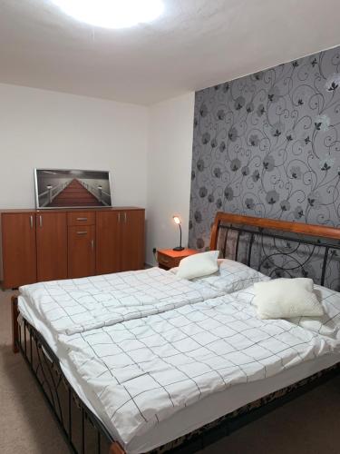 a bedroom with a large bed with white sheets and a wall at Apartmán Vsetín Rokytnice in Vsetín