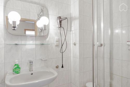 ein weißes Bad mit einem Waschbecken und einer Dusche in der Unterkunft StayINN Lindenau in Leipzig