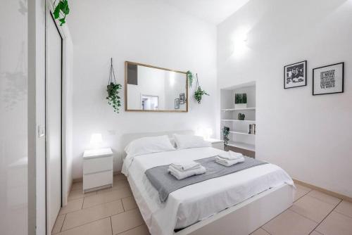 ein weißes Schlafzimmer mit einem Bett und einem Spiegel in der Unterkunft Duomo 10 minutes away - Loft with Wifi and Netflix in Mailand