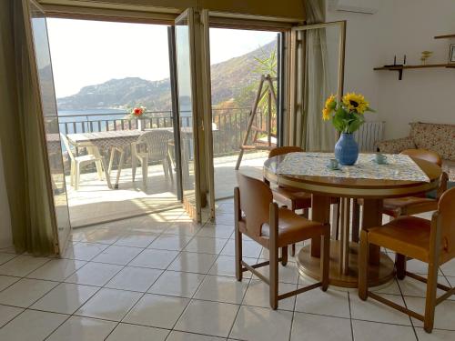 a dining room with a table and a balcony at Collina del Sole in Letojanni