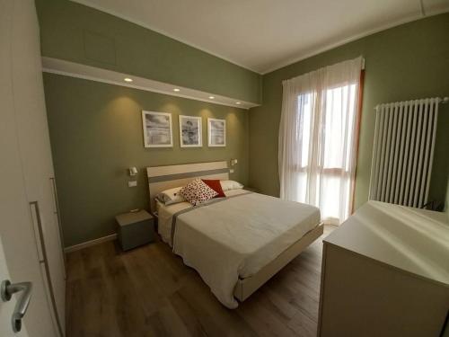 Dormitorio verde con cama y ventana en Appartamento con vista mare, en Cesenatico