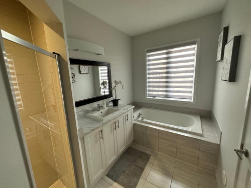 a bathroom with a tub and a sink and a mirror at Modern Townhouse, Vaughan, Ontario, Canada in Vaughan